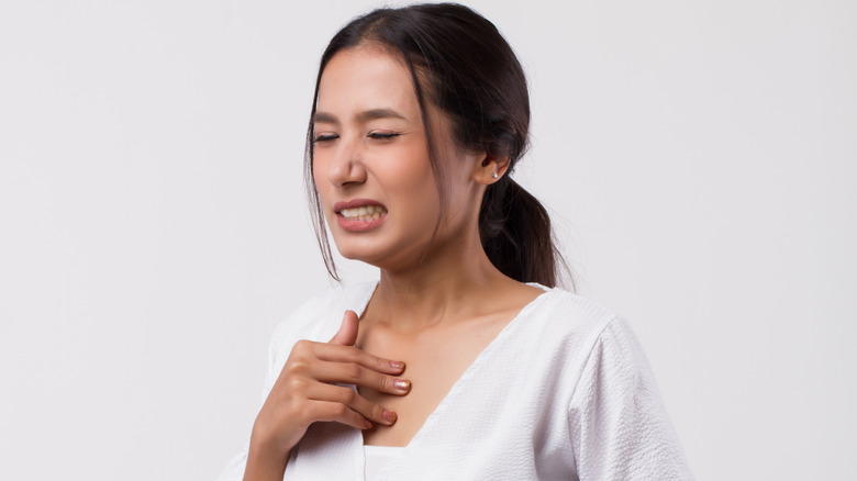 Young woman clutching her chest and stomach in pain