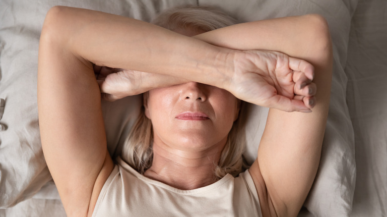 Woman laying in bed with hands over face
