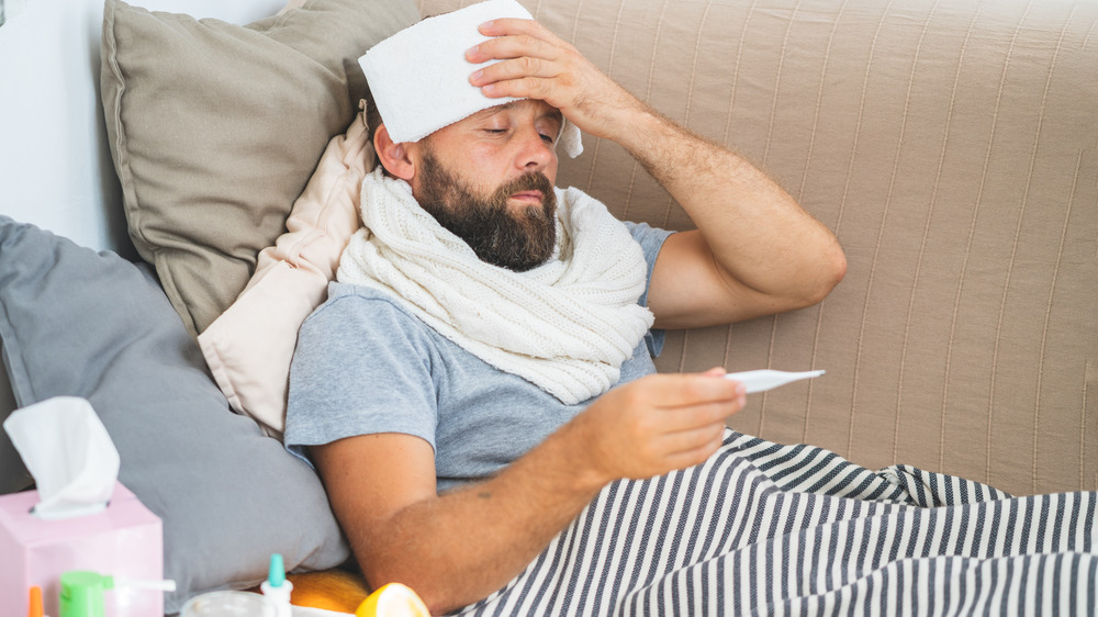 Man with fever taking temperature