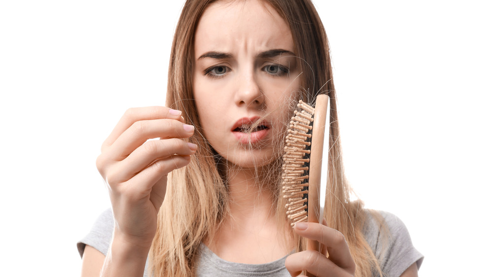 Light haired woman upset over hair in her brush