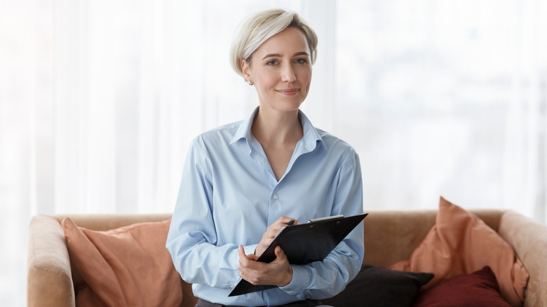 professional psychologist sitting on a sofa with a clipboard