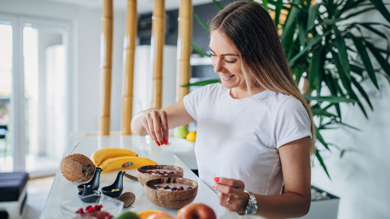 woman adding healthy ingredients to her breakfast bowl