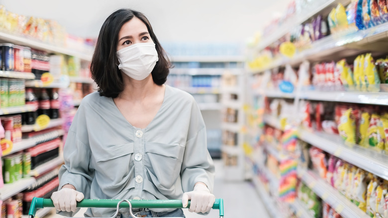 A woman grocery shops while wearing a mask