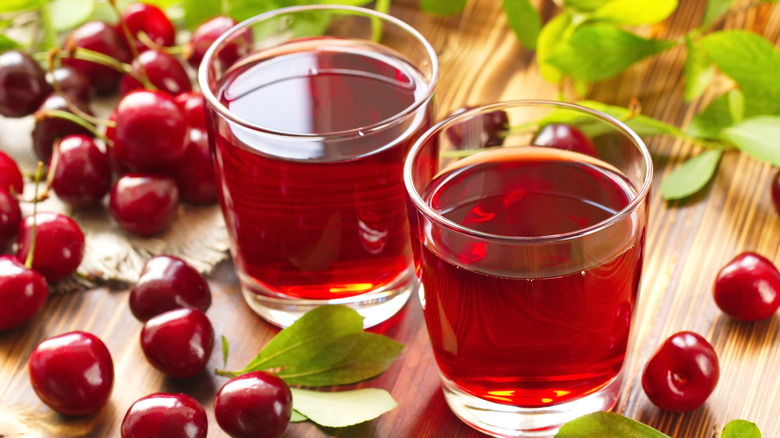 two glasses of tart cherry juice with cherries around them