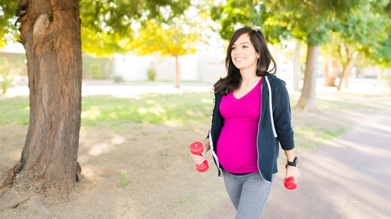 a pregnant women carrying weights and walking 