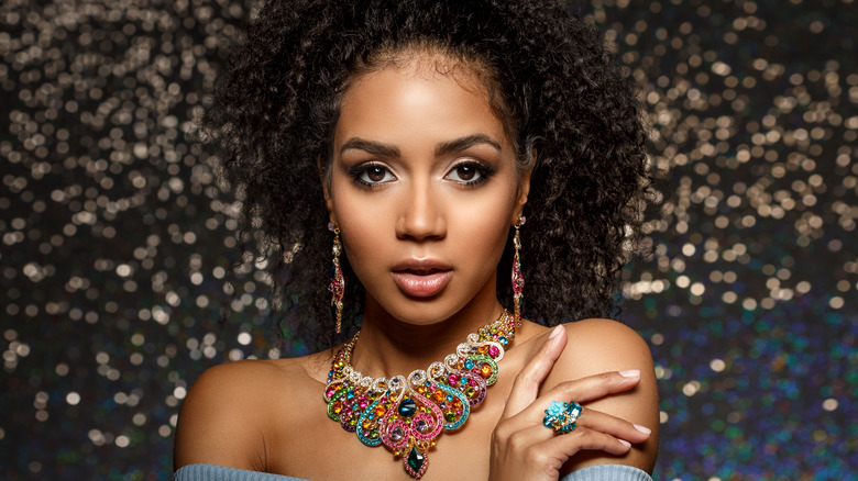 Woman posing with colorful necklace, earrings, and ring on 