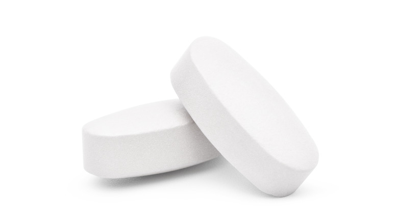 close up of two calcium pills with an all white background 
